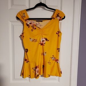 Yellow floral peplum top with cap sleeves and ruched vneck
